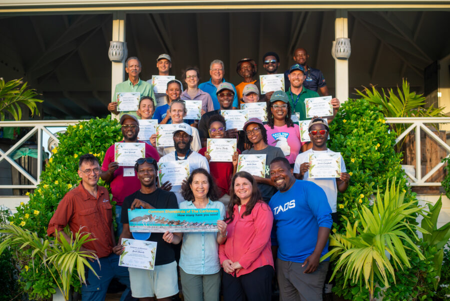 Group of people standing in front of a building holding certificates.